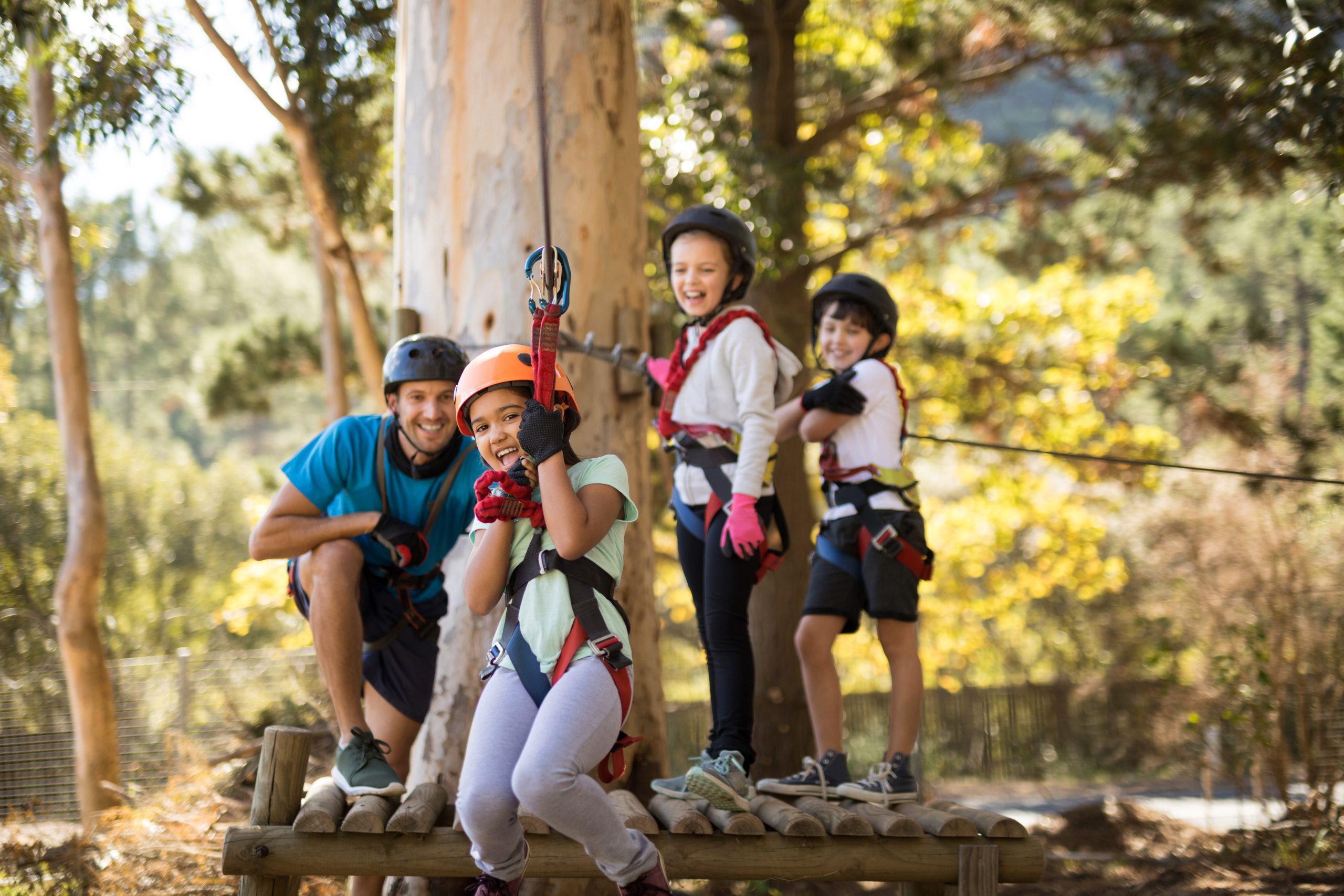 Happy kids enjoying zip line adventure on sunny day